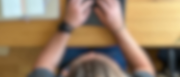 Verschwommenes Bild mit Christoph sitzend vor seinem Laptop. Aufnahme von oben.
